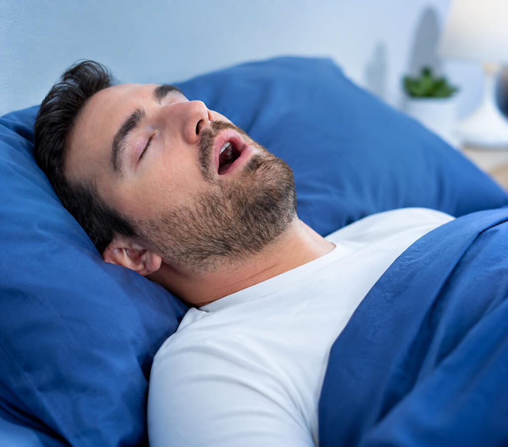 Man snoring in bed showing symptoms of obstructive sleep apnea